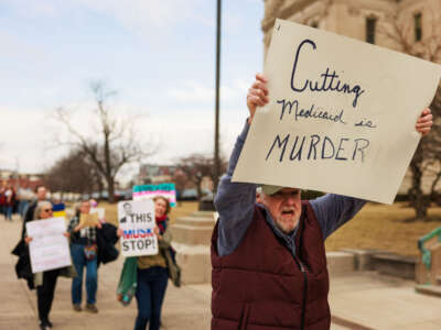 A protester holds a sign reading 'Cutting Medicaid is Murder' during a demonstration against President Donald Trump, Elon Musk and the Trump administration outside the statehouse in Indianapolis, Indiana, on March 4, 2025.