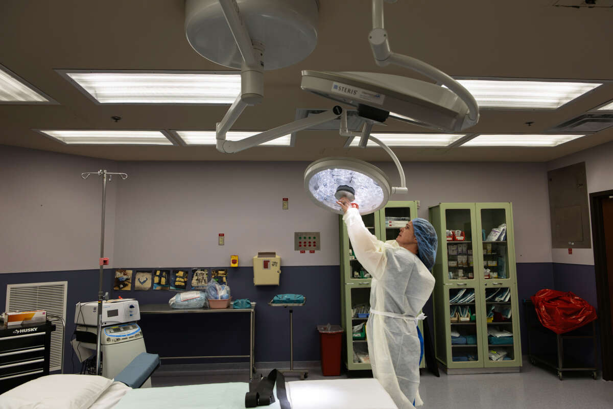 A medical worker adjusts a light in a surgery room