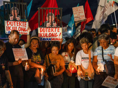 Protesters demonstrate during a candle light vigil demanding justice for drug war victims, after the arrest of former Philippine president Rodrigo Duterte, in Quezon City on March 11, 2025.