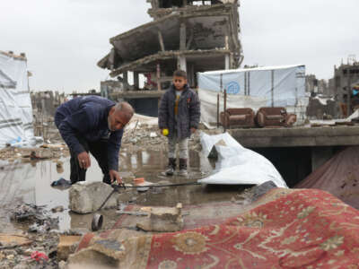 A Palestinian boy watches as a displaced man sets up a tent on a rainy day amid destroyed buildings in Jabalia in the northern Gaza Strip on February 6, 2025, during a truce in the war between Israel and Hamas.