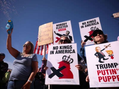 Participants hold signs during the "Shut Down the Coup" protest on the West Lawn of the U.S. Capitol on March 10, 2025, in Washington, D.C.