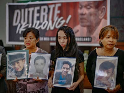 Relatives of drug war victims hold pictures of their loved ones during a gathering on March 12, 2025, in Quezon City, Metro Manila, Philippines.