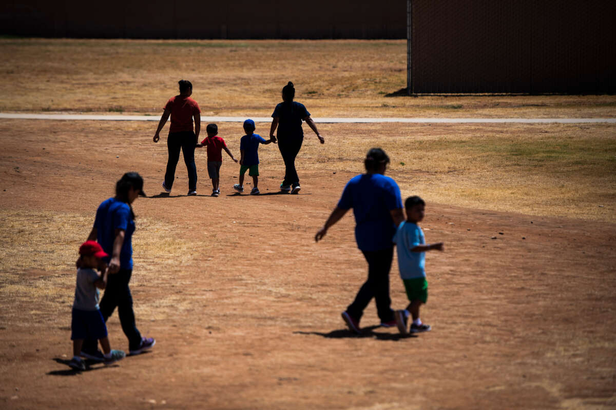 Immigrant women and children walk across a field as U.S. Immigration and Customs Enforcement and Enforcement and Removal Operations host a media tour at the South Texas Family Residential Center on August 23, 2019, in Dilley, Texas.