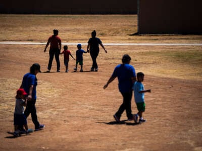 Immigrant women and children walk across a field as U.S. Immigration and Customs Enforcement and Enforcement and Removal Operations host a media tour at the South Texas Family Residential Center on August 23, 2019, in Dilley, Texas.