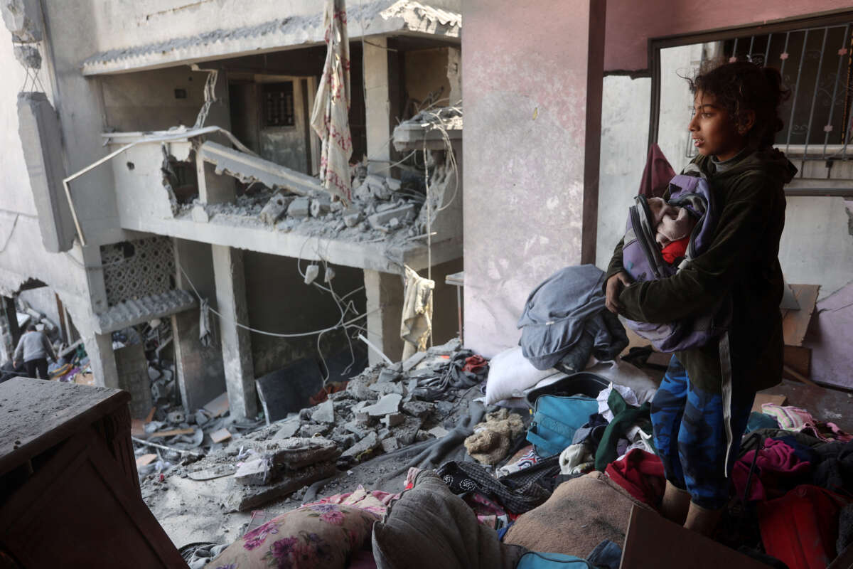 A Palestinian girl salvages items from a damaged house near the Qrayqea family house that was destroyed in Israeli strikes at dawn in the Shujaiya district in eastern Gaza City on March 18, 2025.