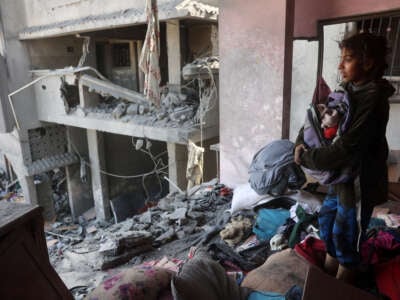 A Palestinian girl salvages items from a damaged house near the Qrayqea family house that was destroyed in Israeli strikes at dawn in the Shujaiya district in eastern Gaza City on March 18, 2025.