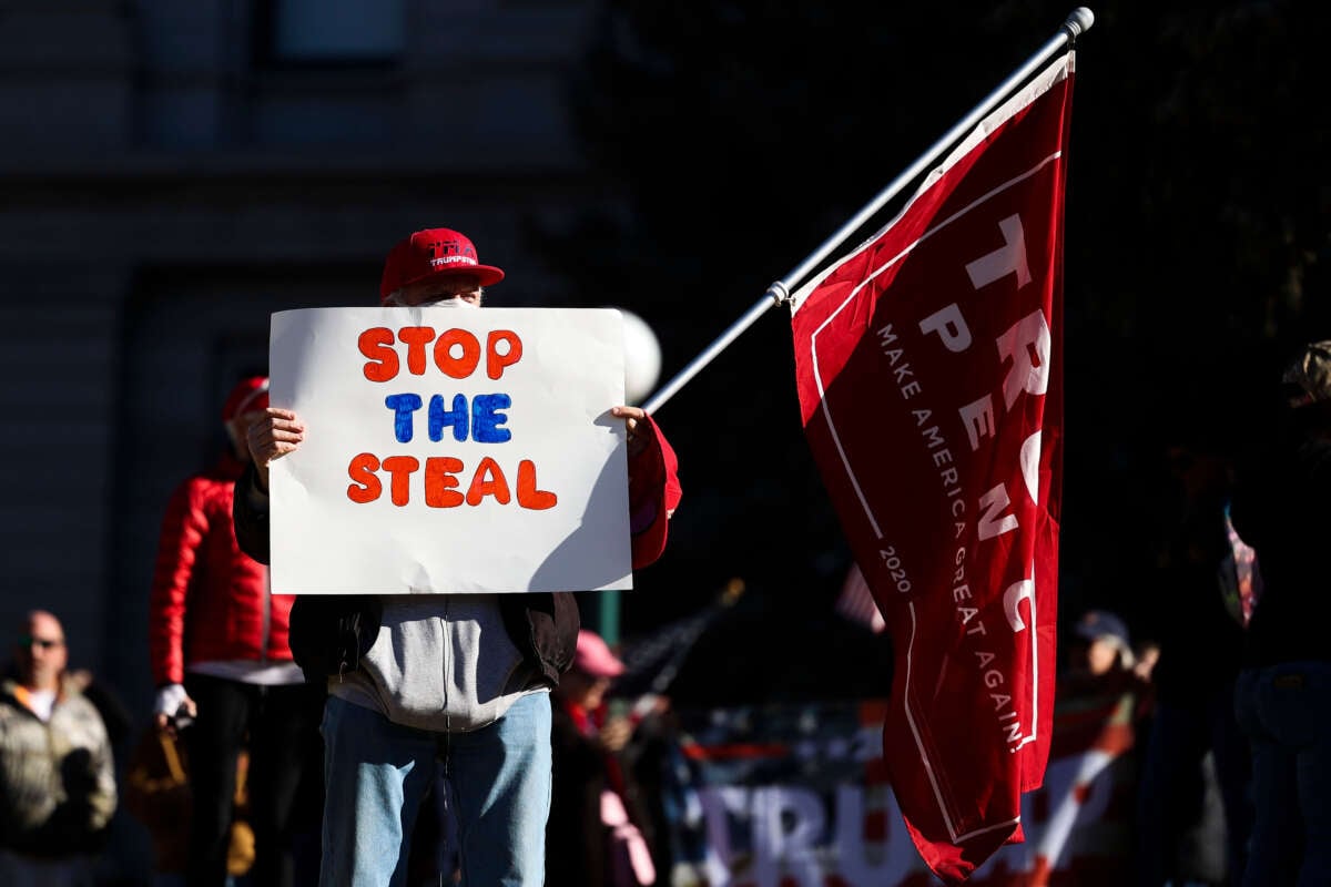 A Donald Trump supporter holds a Stop the Steal sign while gathering on the steps of the Colorado State Capitol to protest the election on January 6, 2021, in Denver, Colorado.