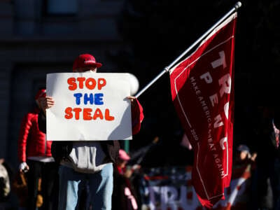 A Donald Trump supporter holds a Stop the Steal sign while gathering on the steps of the Colorado State Capitol to protest the election on January 6, 2021, in Denver, Colorado.