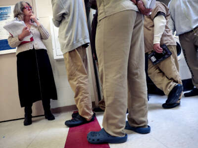 People in beige prison uniforms talk to a case worker