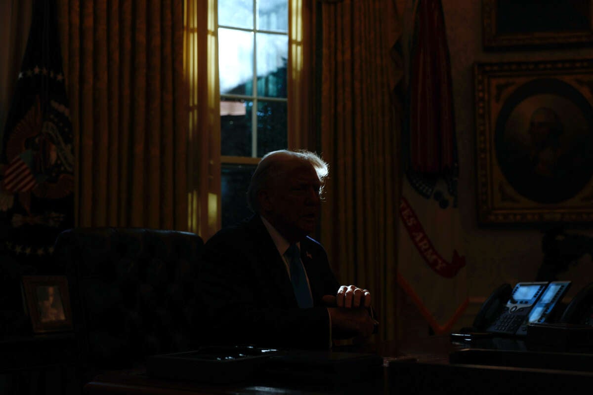 Donald Trump sits in a darkened oval office