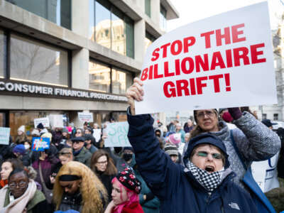 Demonstrators hold signs as they attend a protest against President Donald Trump and Elon Musk's anticipated plan to close the Consumer Financial Protection Bureau (CFPB) in front of the CFPB headquarters in Washington, D.C., on February 10, 2025.