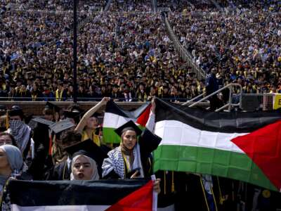 Salma Hamamy, center, holds a flag of Palestine during the University of Michigan's spring commencement ceremony on May 4, 2024, at Michigan Stadium in Ann Arbor, Michigan.