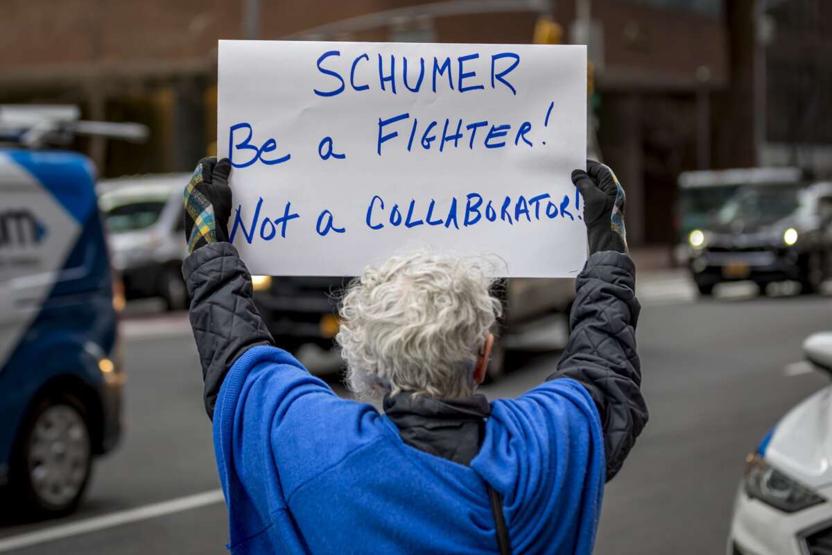 An activist protests outside the office of Senate Minority Leader Chuck Schumer on March 14, 2025.