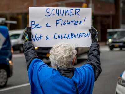 An activist protests outside the office of Senate Minority Leader Chuck Schumer on March 14, 2025.