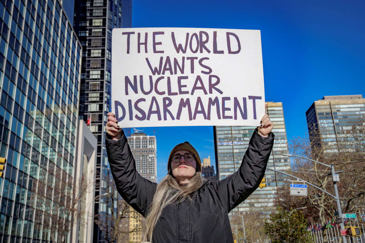 A person holds a sign reading "THE WORLD WANTS NUCLEAR DISARMAMENT" during an outdoor protest