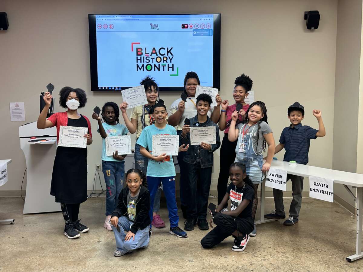 Students raise their fists during a Black History Month jeopardy game at For the Culture in San Antonio, Texas.