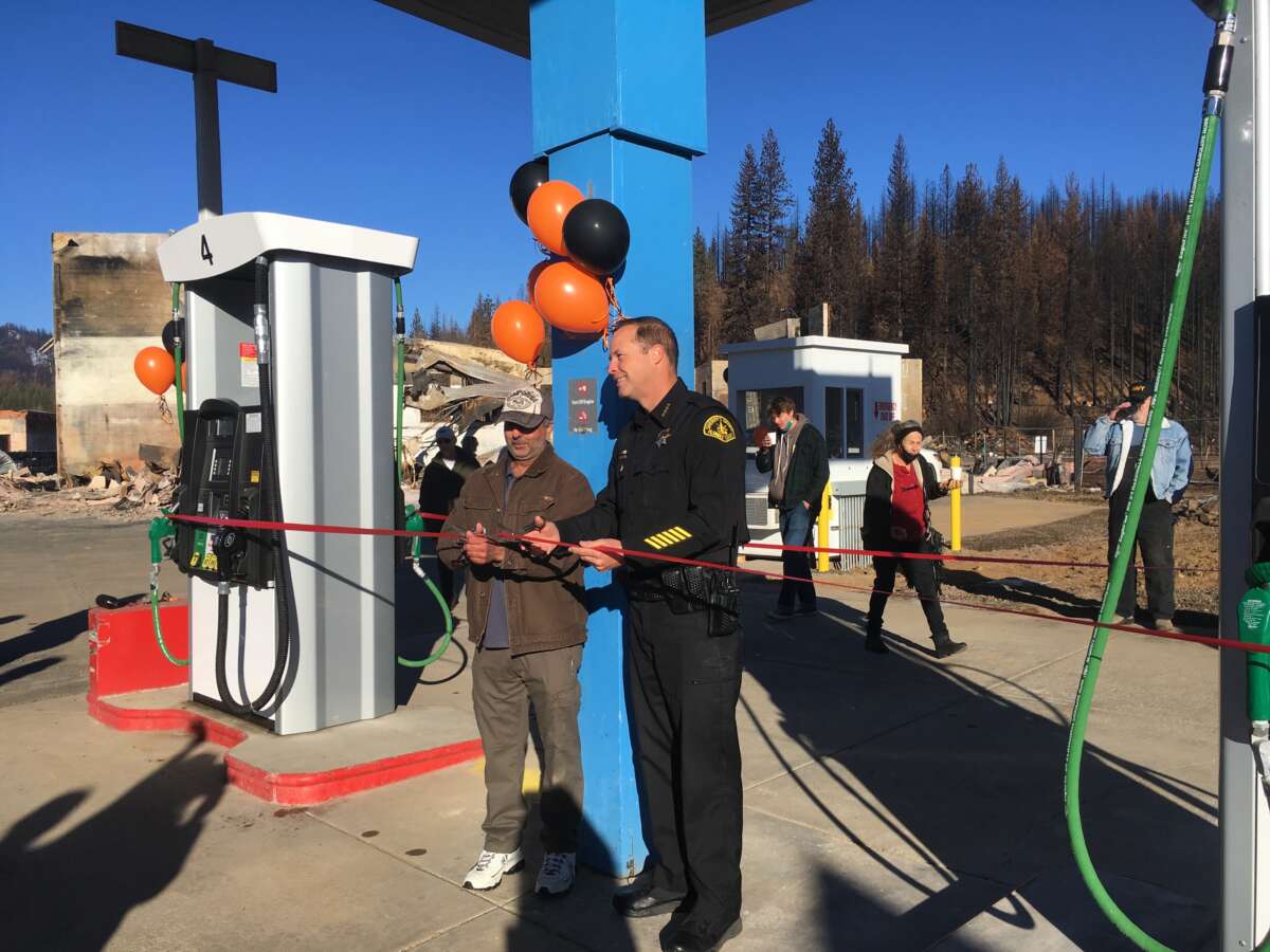Sheriff Todd Johns and business owner Pete Singh hold a community ribbon-cutting to mark the first business to reopen after the fire.
