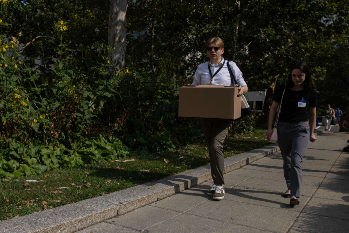 Recently laid off U.S. State Department employees carry boxes as they walk out of the Harry S. Truman Federal Building on July 11, 2025 in Washington, D.C.