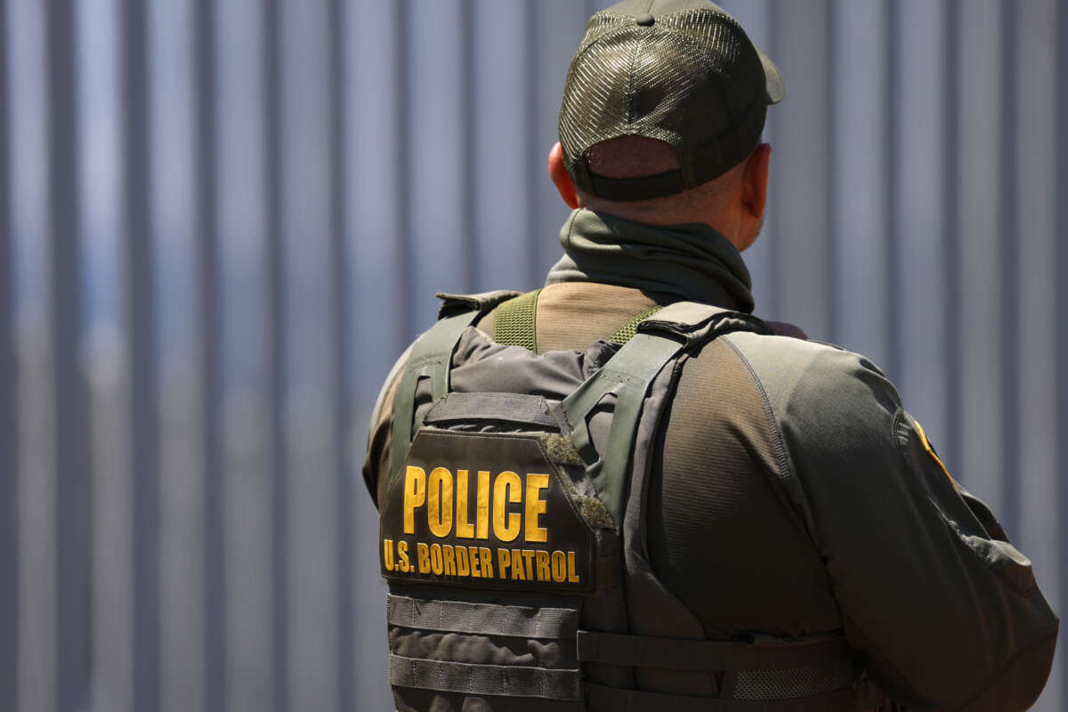 A Border Patrol agent stands at Border Field State Park with the U.S.-Mexico border wall in the background on August 17, 2025.