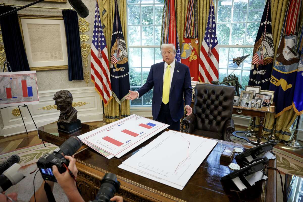 President Donald Trump speaks in front of posters depicting household income data in the Oval Office on August 7, 2025.