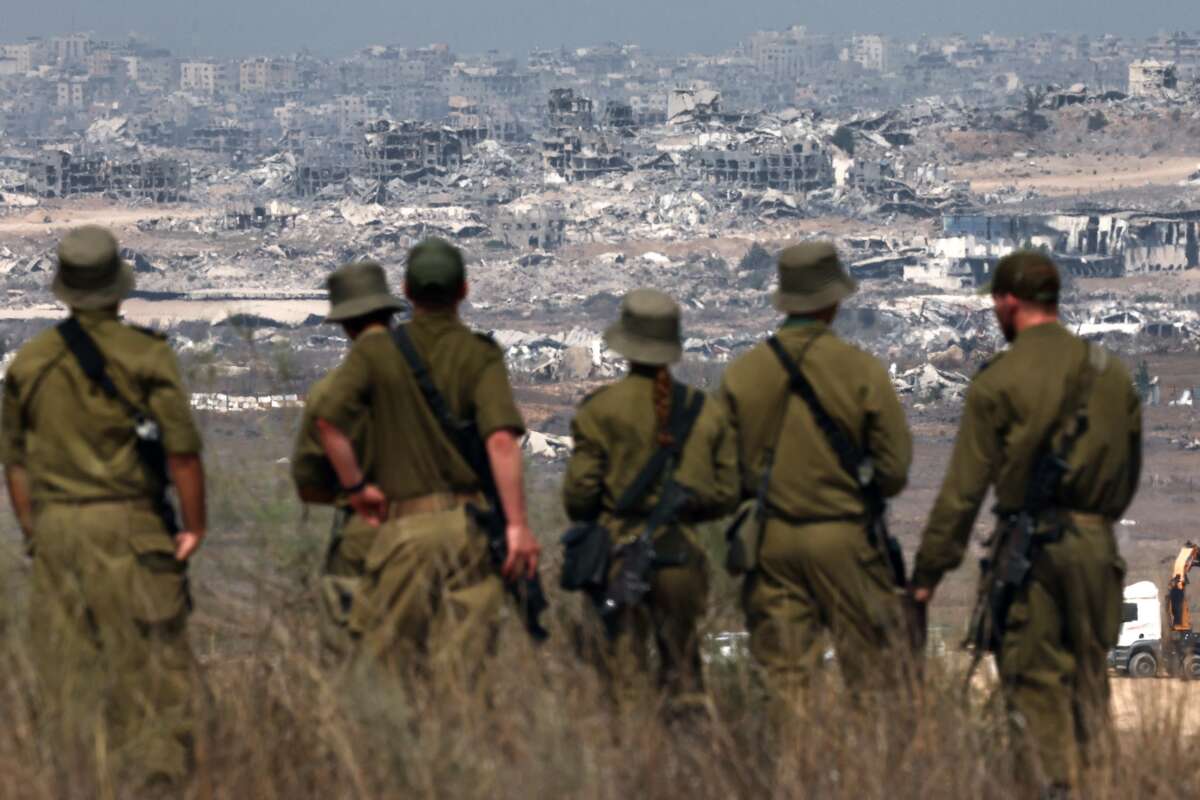 Israeli soldiers look at destroyed buildings in the Gaza Strip as they stand on the border with the Palestinian territory, on August 13, 2025.