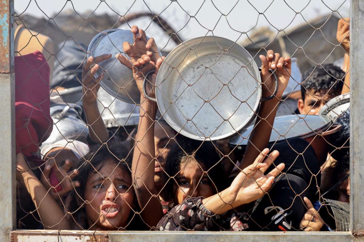 Palestinians, mostly children, push to receive a hot meal at a charity kitchen in the Mawasi area of Khan Yunis in the southern Gaza Strip on July 22, 2025.