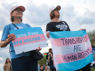 Two people are holding the transgender flag.