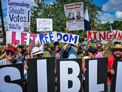 People take part in a "Fight the Trump Takeover" rally, part of a national day of action, in Wilton Manors, Florida, on August 16, 2025. The national day of action was planned after weeks of maneuvering in Texas, where Gov. Greg Abbott -- acting at Donald Trump's behest -- is trying to redraw electoral districts to benefit his Republican Party.