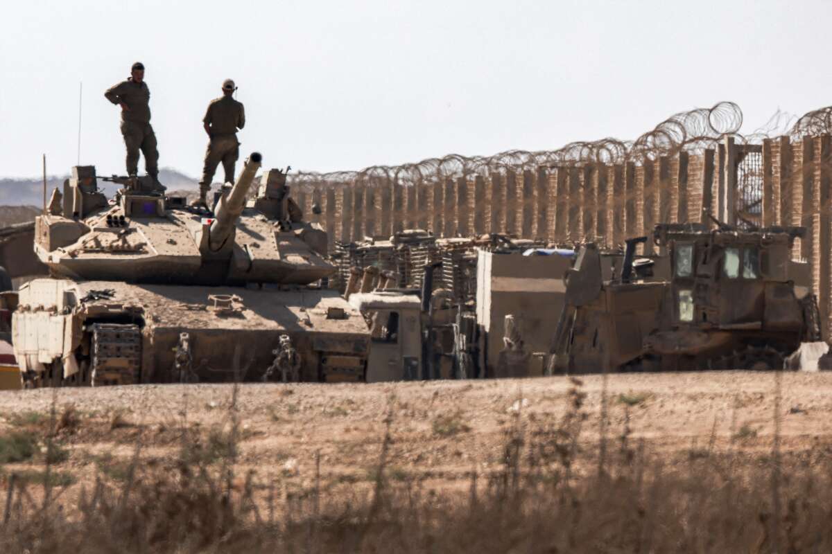 Israeli army soldiers stand atop the turret of a Merkava main battle tank positioned near armored military bulldozers along the border with the Gaza Strip in southern Israel on September 2, 2025.