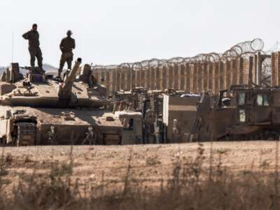 Israeli army soldiers stand atop the turret of a Merkava main battle tank positioned near armored military bulldozers along the border with the Gaza Strip in southern Israel on September 2, 2025.