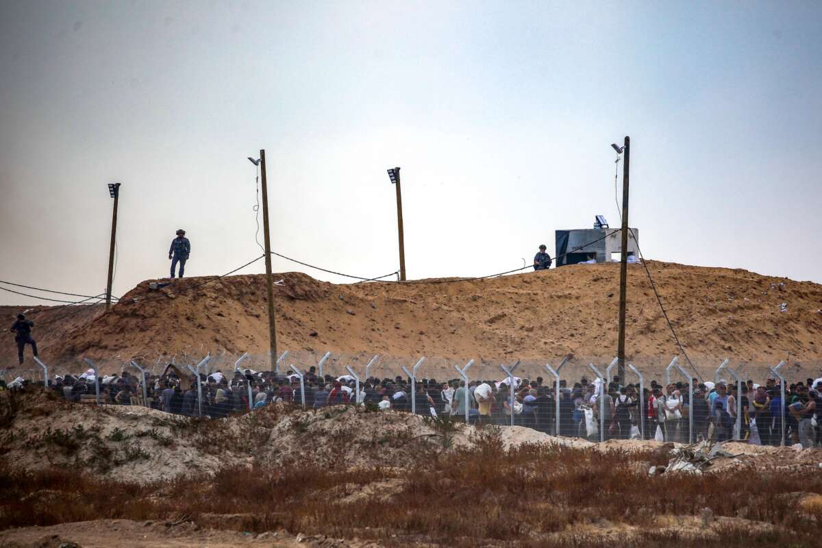 Members of a private US security company, contracted by the Gaza Humanitarian Foundation (GHF) direct displaced Palestinians as they gather to receive relief supplies at a distribution center in the central Gaza Strip on June 8, 2025.