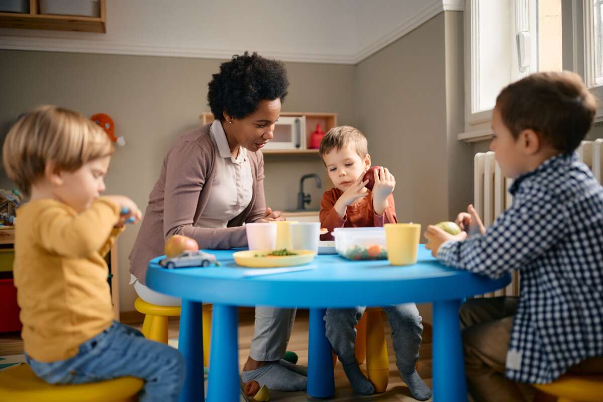 Group of kids eating fruit with their teacher