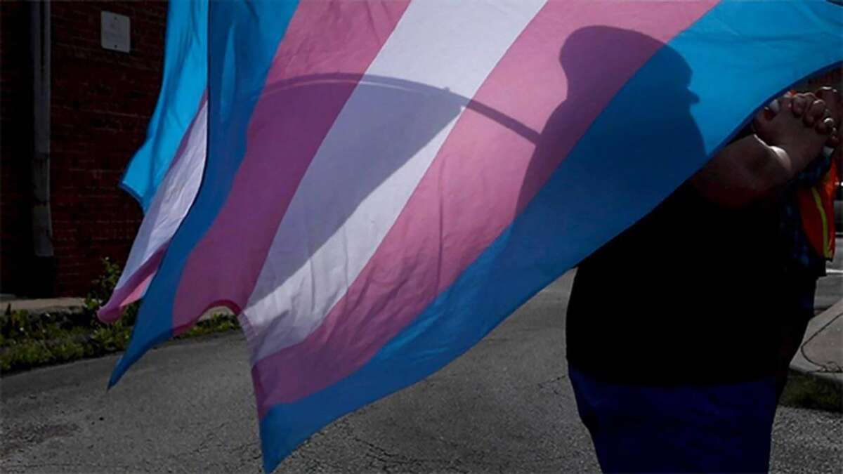 A marcher carries a Transgender Pride flag during a march in Kansas City.