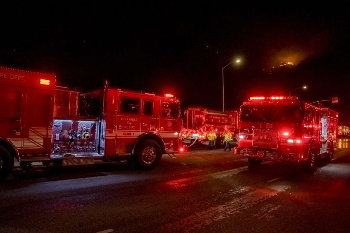 Fire trucks line the street as flames burn through vegetation in the Sepulveda Pass near Highway 405 in Los Angeles, California, on January 24, 2025.
