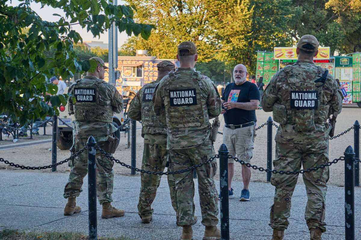 A Washington, D.C., resident speaks with National Guard soldiers stationed outside of the Smithsonian Metro station on August 30, 2025, after Donald Trump ordered federal agents and the National Guard to perform basic policing actions throughout the city.