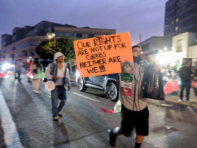 Protesters are on the street and one protester is holding an orange sign that reads "Our rights are not up for grabs and neither are we."