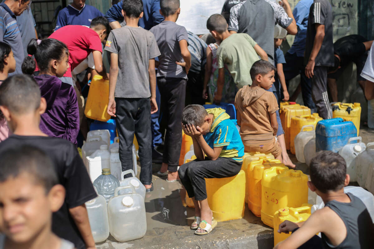 Palestinian children sit on their containers as they queue for water at a charity distribution point in the Nuseirat refugee camp in the Israel-besieged Gaza Strip on September 4, 2025.