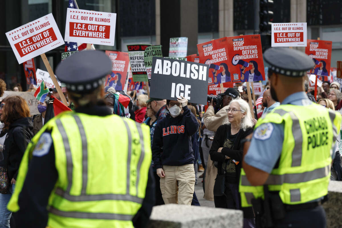 Police officers watch as people participate in a demonstration against the planned deployment of National Guard troops in Chicago