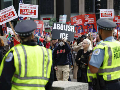 Police officers watch as people participate in a demonstration against the planned deployment of National Guard troops in Chicago
