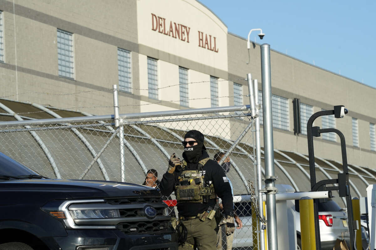 Immigration and Customs Enforcement (ICE) agents stand near a gate as they watch protestors at a demonstration in Newark, New Jersey May 7, 2025, outside Delaney Hall.