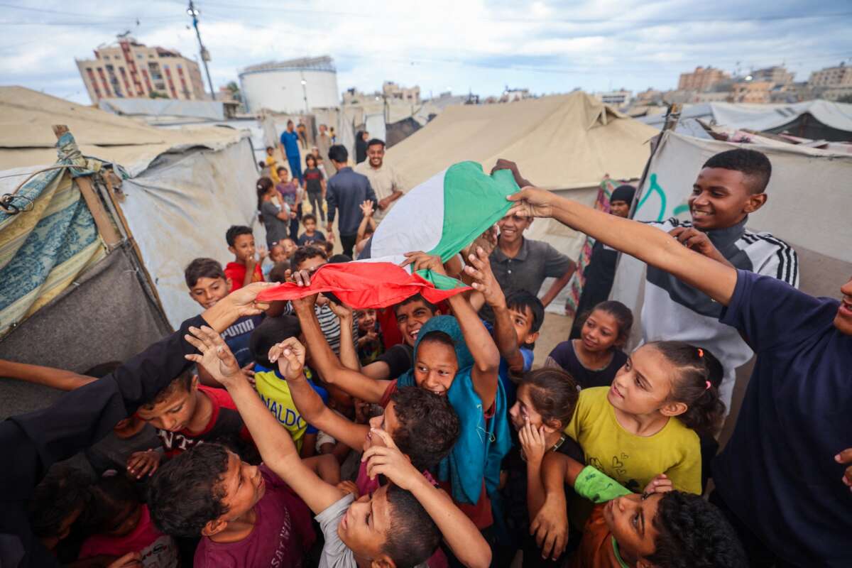 Palestinian children celebrate at a camp for displaced people in Nuseirat in the central Gaza Strip on October 9, 2025, following news of a new Gaza ceasefire deal.
