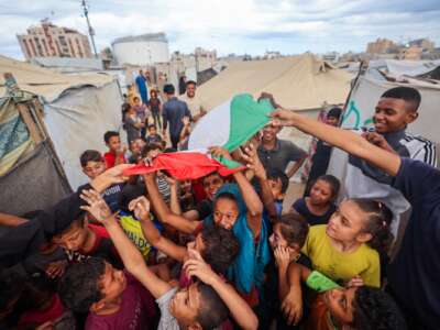 Palestinian children celebrate at a camp for displaced people in Nuseirat in the central Gaza Strip on October 9, 2025, following news of a new Gaza ceasefire deal.