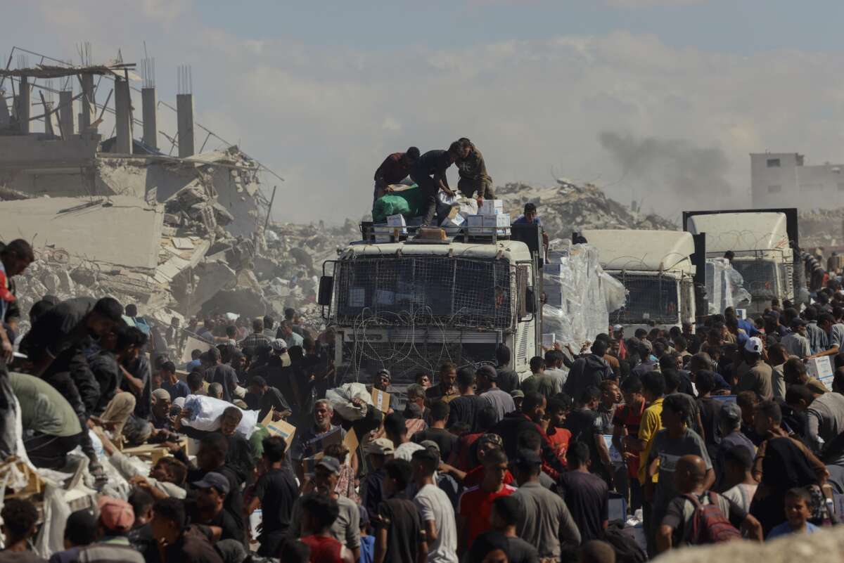 People walk through a heavily damaged street in Khan Younis, southern Gaza Strip, on October 12, 2025. Aid entered Gaza through the Kerem Shalom crossing toward Khan Younis, where residents rushed to seize supplies amid ongoing shortages.