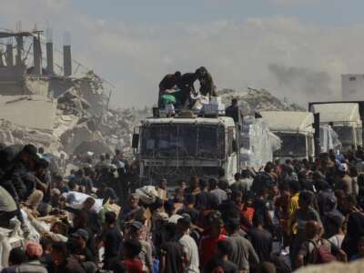 People walk through a heavily damaged street in Khan Younis, southern Gaza Strip, on October 12, 2025. Aid entered Gaza through the Kerem Shalom crossing toward Khan Younis, where residents rushed to seize supplies amid ongoing shortages.