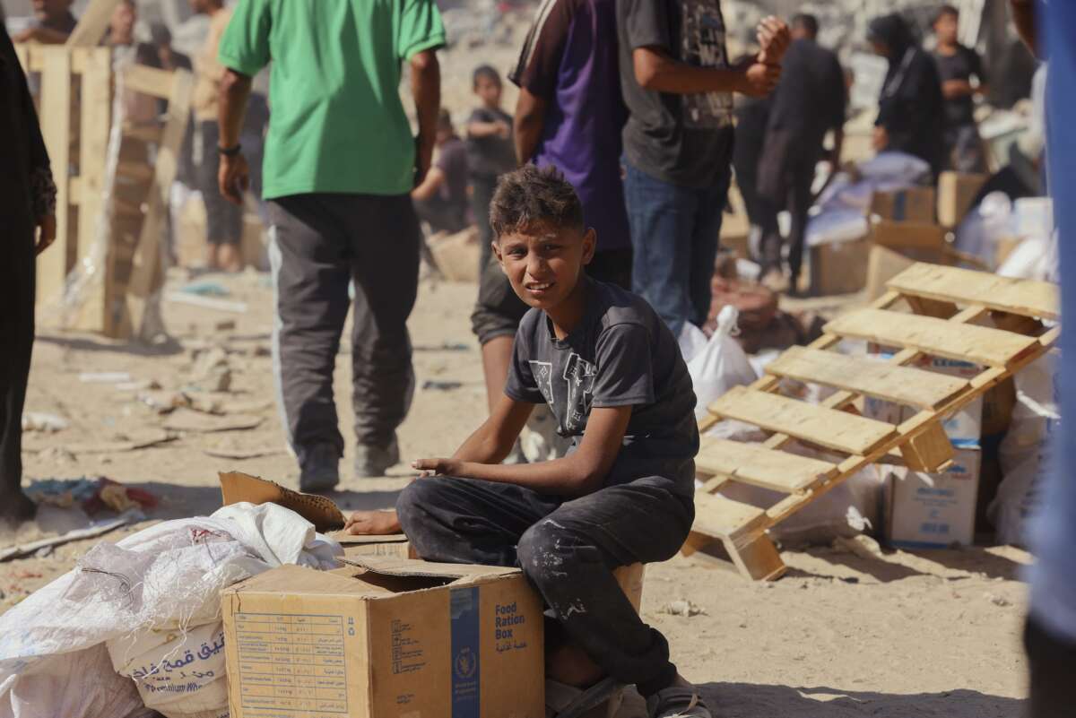 People walk through a heavily damaged street in Khan Younis, southern Gaza Strip, on October 12, 2025. Aid entered Gaza through the Kerem Shalom crossing toward Khan Younis, where residents rushed to seize supplies amid ongoing shortages.