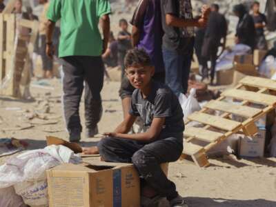 People walk through a heavily damaged street in Khan Younis, southern Gaza Strip, on October 12, 2025. Aid entered Gaza through the Kerem Shalom crossing toward Khan Younis, where residents rushed to seize supplies amid ongoing shortages.