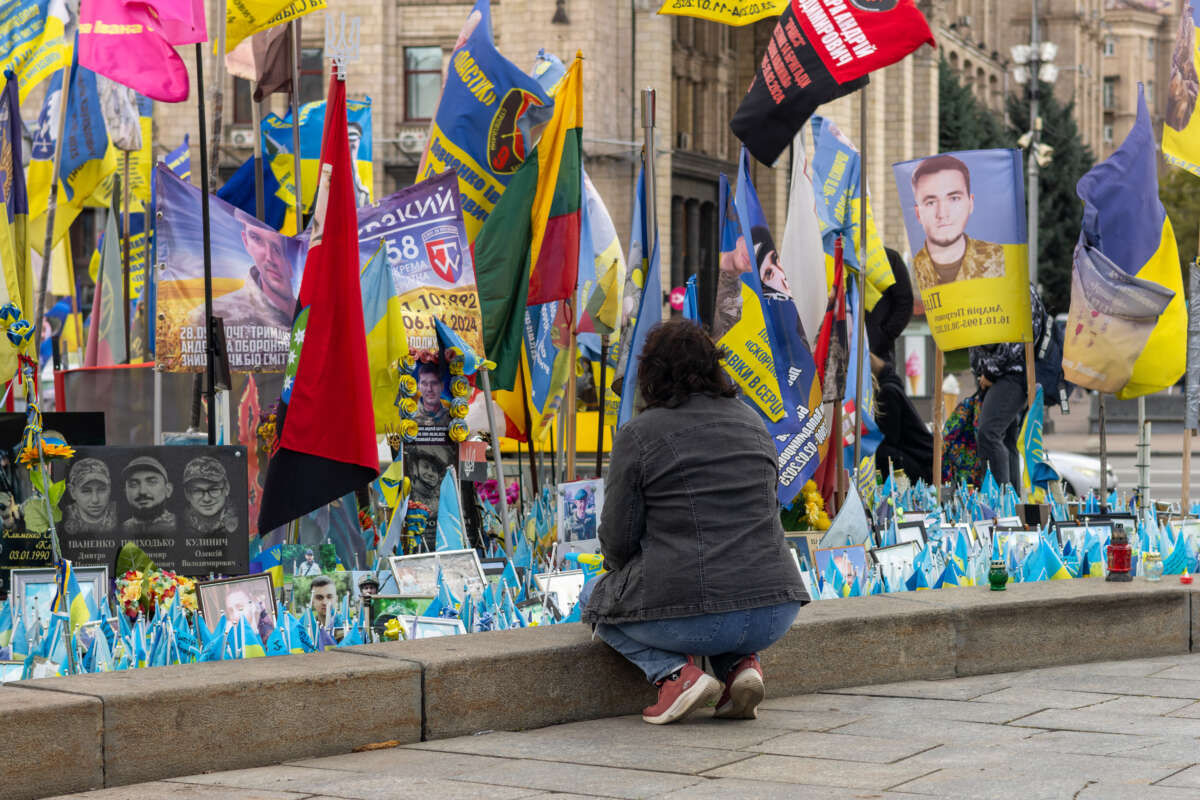 A woman kneels at the makeshift memorial at Independence Square.