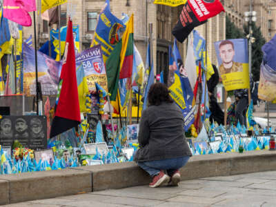 A woman kneels at the makeshift memorial at Independence Square.