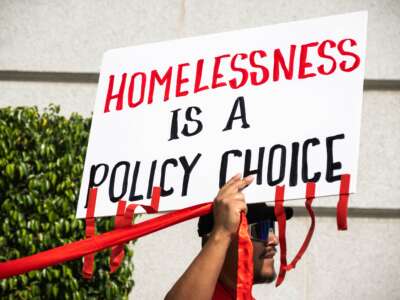 Housing advocates wrap red ribbons around Los Angeles City Hall to symbolize how red tape prevents affordable housing, on April 22, 2025.