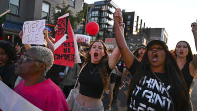 Protesters hold hands and shout slogans as they walk down U Street during an "End the DC Occupation" rally against U.S. President Donald Trump and his use of emergency powers to take over the D..C Police in Washington, D.C., on August 23, 2025.
